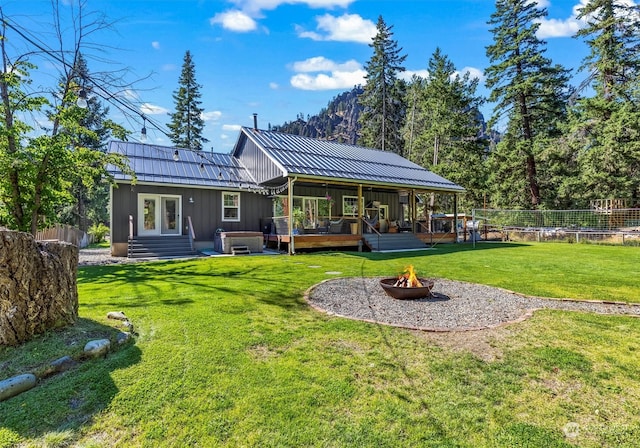 back of property with a lawn, a fire pit, and a deck