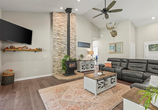 living room featuring high vaulted ceiling, dark hardwood / wood-style floors, a wood stove, and ceiling fan