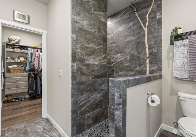 bathroom featuring hardwood / wood-style flooring, toilet, and tiled shower