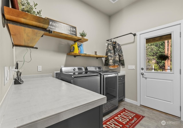 laundry area featuring cabinets, washing machine and dryer, and light hardwood / wood-style flooring