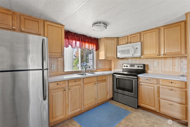 kitchen with a textured ceiling, appliances with stainless steel finishes, sink, and light brown cabinetry