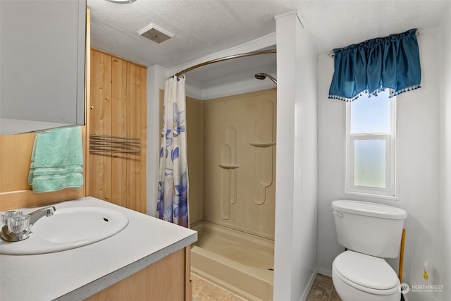 bathroom with tile patterned flooring, a textured ceiling, curtained shower, vanity, and toilet