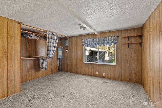 carpeted empty room with wood walls