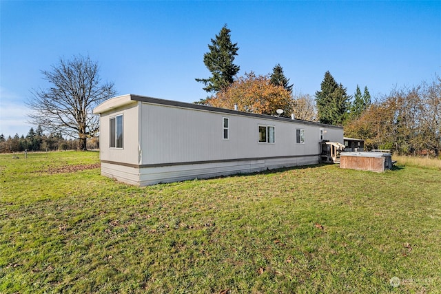 rear view of property featuring a hot tub and a yard