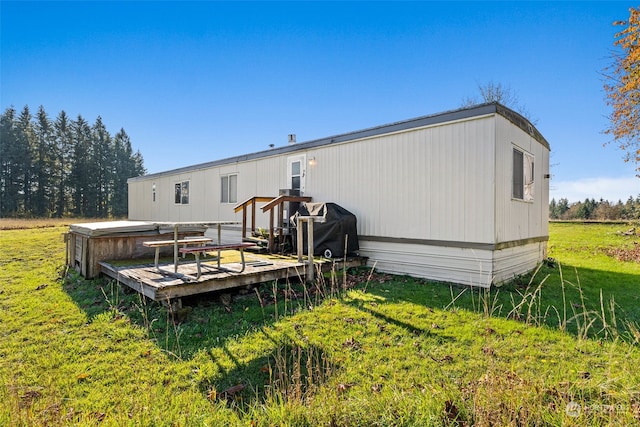 rear view of property featuring a lawn and a wooden deck