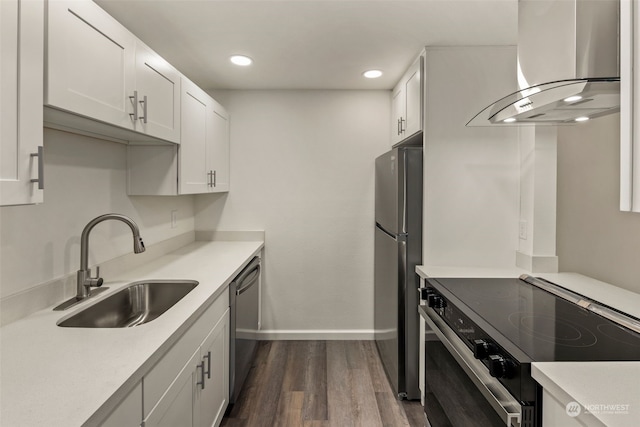 kitchen featuring wall chimney range hood, sink, white cabinets, appliances with stainless steel finishes, and dark hardwood / wood-style flooring