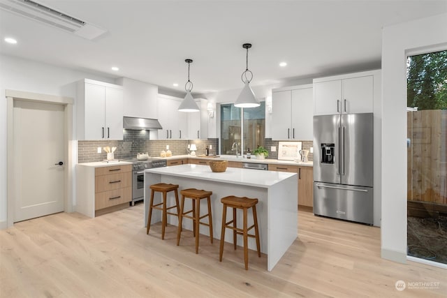 kitchen featuring appliances with stainless steel finishes, hanging light fixtures, and white cabinets