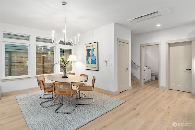 dining area with light hardwood / wood-style floors and a chandelier