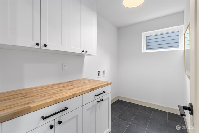 laundry area featuring hookup for a washing machine, cabinets, and dark tile patterned floors