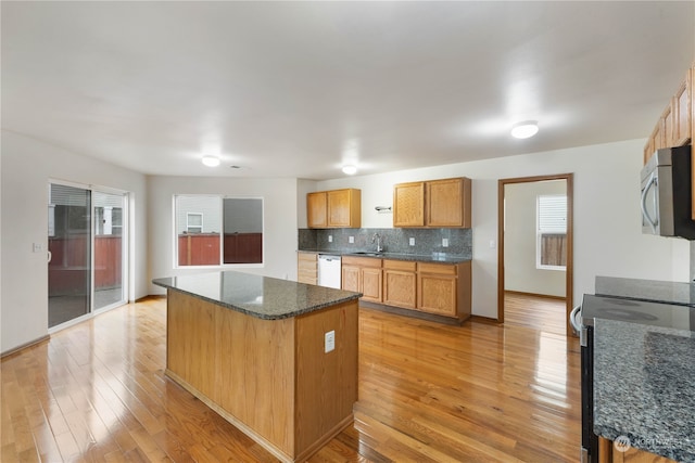 kitchen with backsplash, a center island, light wood-type flooring, and range