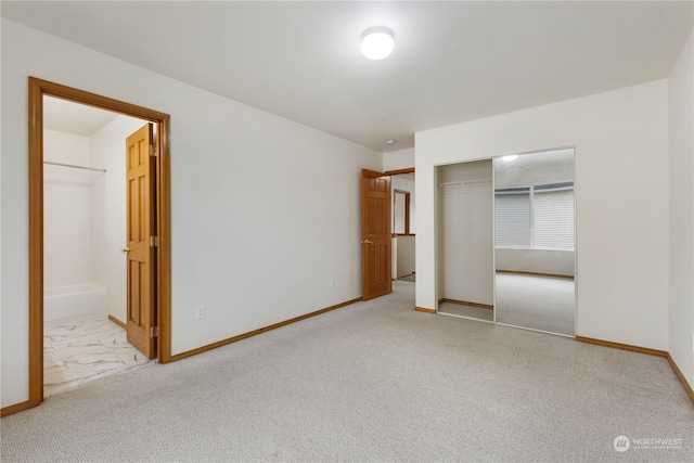 unfurnished bedroom with light carpet, a closet, and ensuite bath