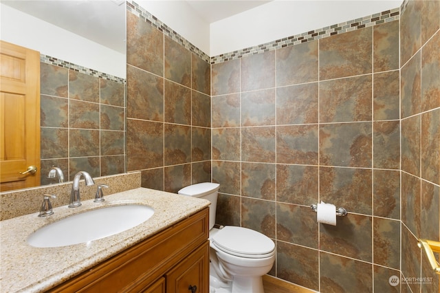 bathroom with tile walls, vanity, and toilet