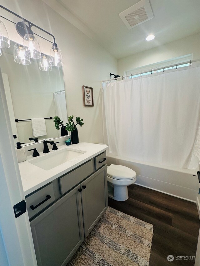 full bathroom featuring hardwood / wood-style floors, vanity, toilet, and shower / bath combo