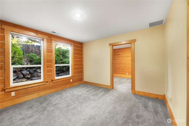 carpeted empty room featuring wooden walls