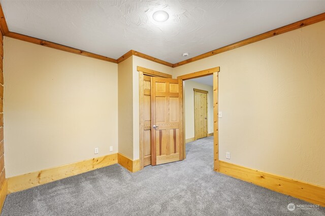 unfurnished room featuring a textured ceiling, ornamental molding, and carpet floors