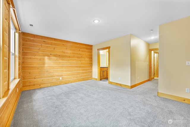 unfurnished room with light carpet and wood walls