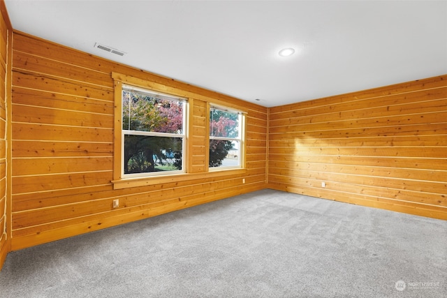 unfurnished room featuring carpet and wooden walls