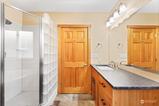 bathroom featuring a shower with door and vanity