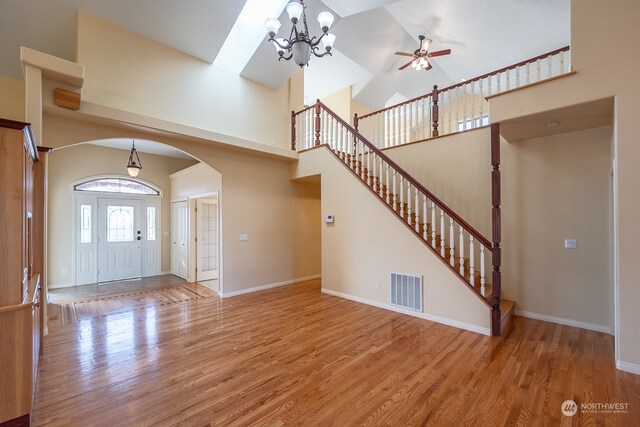 entrance foyer featuring hardwood / wood-style flooring, high vaulted ceiling, and ceiling fan with notable chandelier