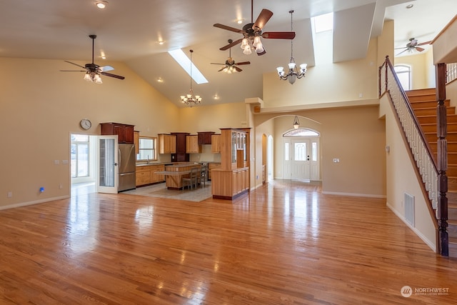 unfurnished living room featuring light hardwood / wood-style flooring, a chandelier, high vaulted ceiling, and plenty of natural light