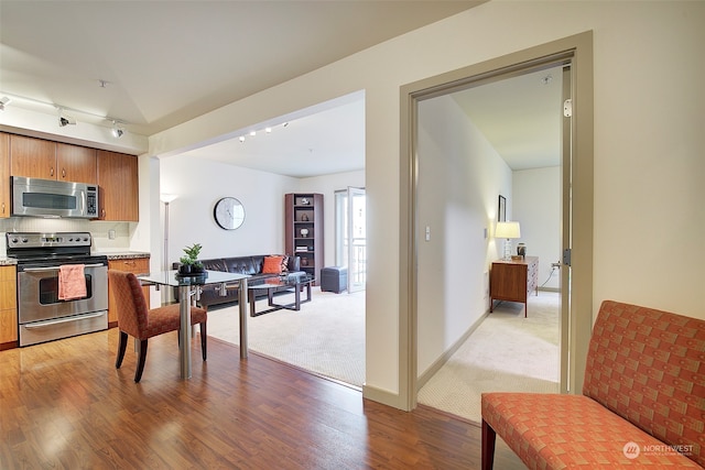 kitchen with hardwood / wood-style floors, stainless steel appliances, and rail lighting