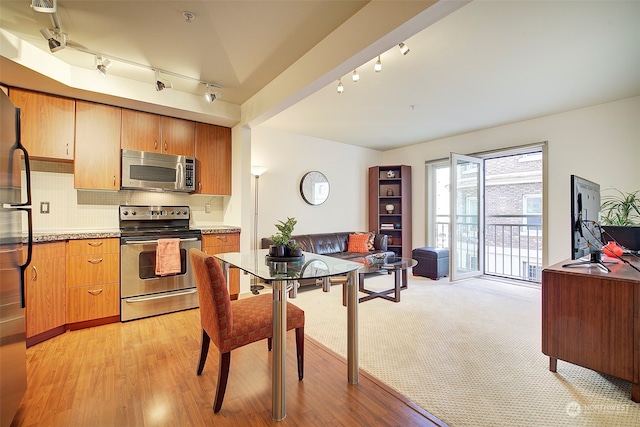 kitchen with light hardwood / wood-style flooring, rail lighting, stainless steel appliances, and backsplash