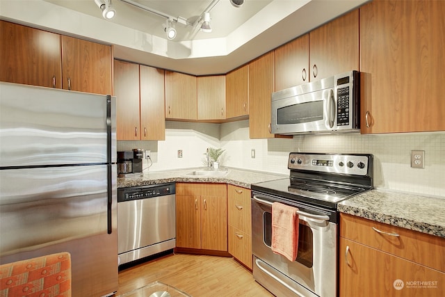 kitchen featuring light hardwood / wood-style flooring, stainless steel appliances, sink, rail lighting, and light stone counters