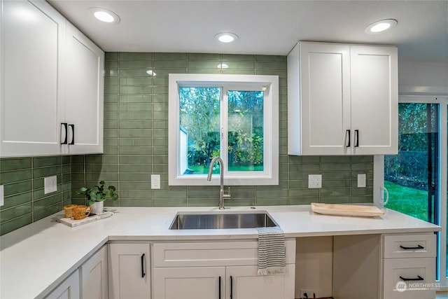 kitchen featuring backsplash, sink, and white cabinets