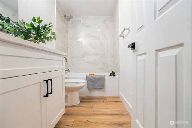 bathroom featuring tiled shower / bath combo, wood-type flooring, and toilet