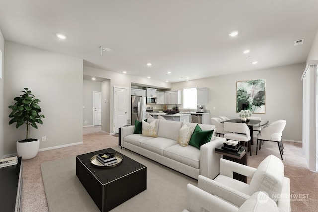 living area featuring recessed lighting, light colored carpet, and baseboards