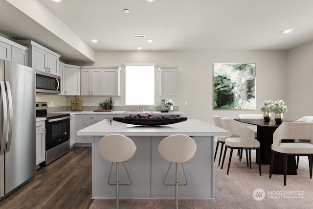 kitchen with visible vents, a kitchen breakfast bar, a kitchen island, appliances with stainless steel finishes, and light countertops