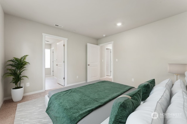 bedroom featuring visible vents, baseboards, light colored carpet, and connected bathroom