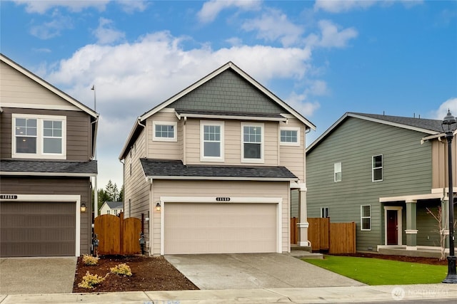 craftsman house with driveway, a shingled roof, an attached garage, and fence