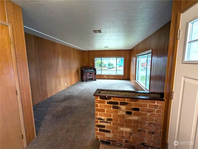 living room featuring wood walls, carpet flooring, and lofted ceiling