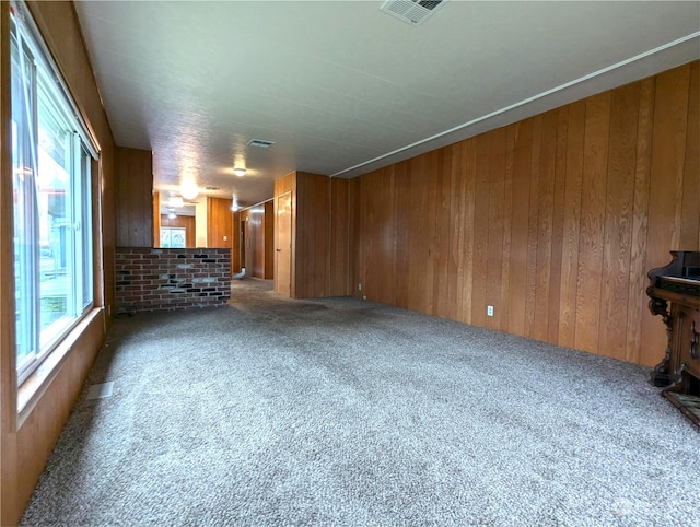 unfurnished living room featuring wood walls and carpet flooring