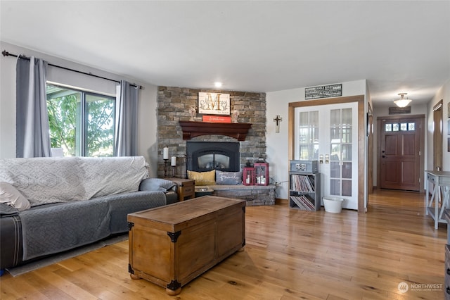 living room featuring a fireplace, light hardwood / wood-style floors, and french doors