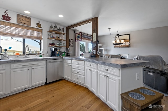 kitchen featuring white cabinetry, sink, stainless steel dishwasher, light hardwood / wood-style floors, and kitchen peninsula