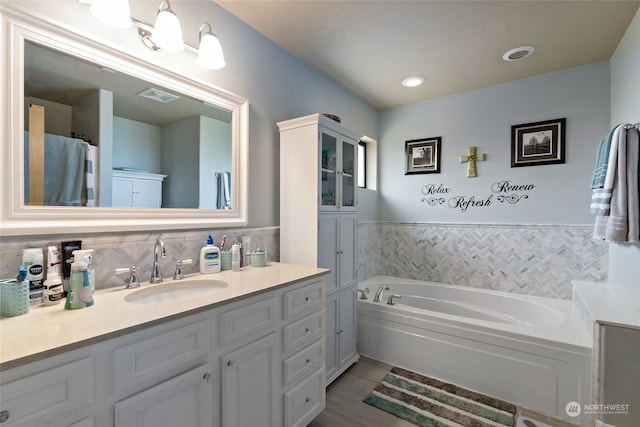 bathroom with a bathing tub, tile walls, and vanity