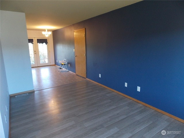 empty room featuring hardwood / wood-style flooring, french doors, and a notable chandelier