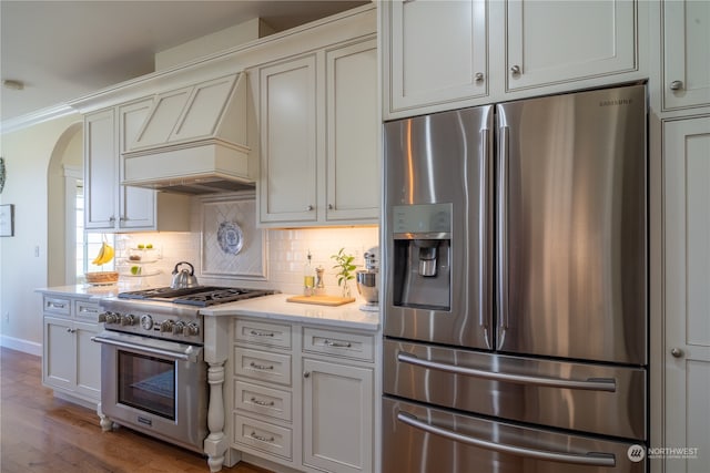 kitchen featuring stainless steel appliances, crown molding, light wood-type flooring, white cabinets, and tasteful backsplash