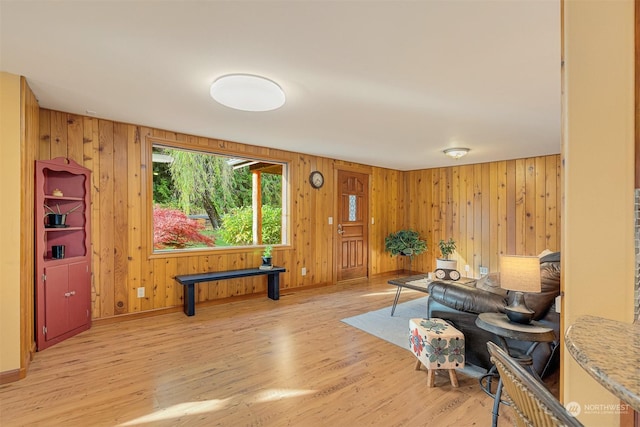 living area featuring baseboards, wooden walls, and light wood-style flooring
