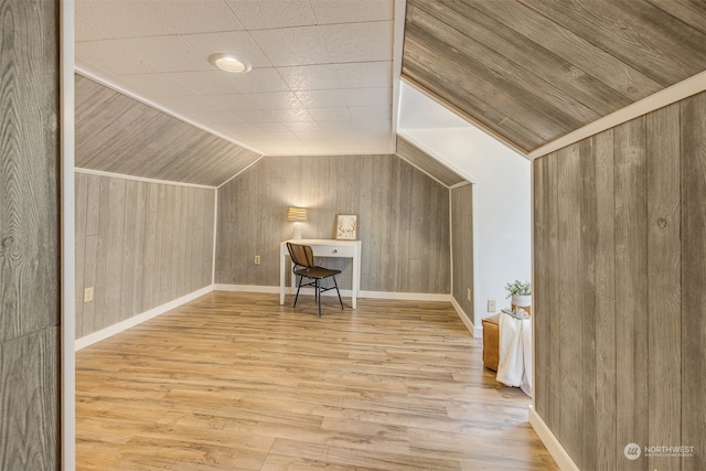 bonus room featuring lofted ceiling, wood walls, built in desk, and light wood-type flooring