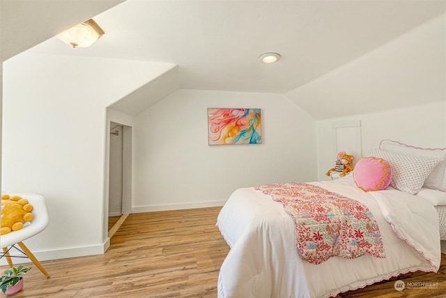 bedroom featuring lofted ceiling, light wood-style flooring, and baseboards