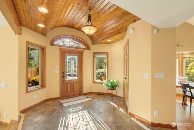 foyer entrance with baseboards, stone tile flooring, wooden ceiling, and vaulted ceiling