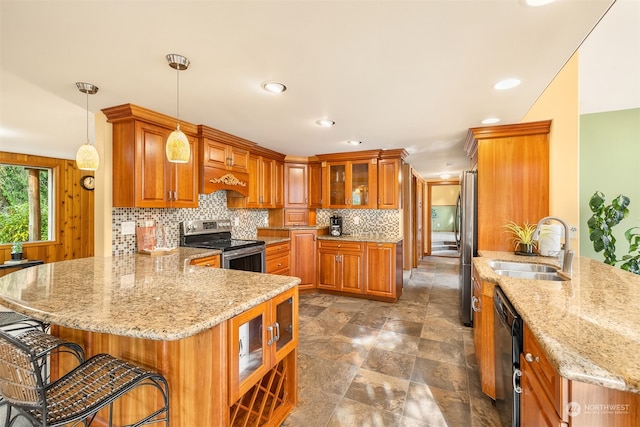 kitchen with kitchen peninsula, light stone countertops, stainless steel appliances, sink, and decorative light fixtures