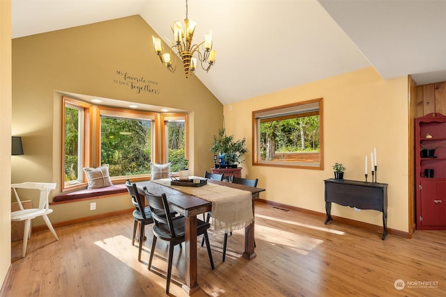 dining area with light wood-type flooring, a wealth of natural light, a chandelier, and high vaulted ceiling