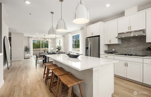 kitchen featuring black electric stovetop, stainless steel fridge with ice dispenser, a kitchen island, and hanging light fixtures