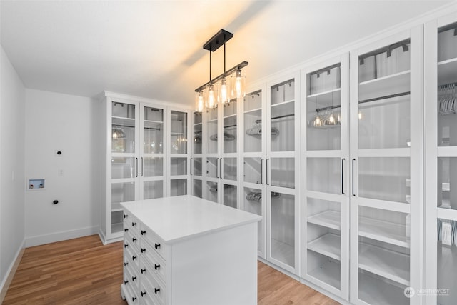 spacious closet featuring an inviting chandelier and light hardwood / wood-style floors