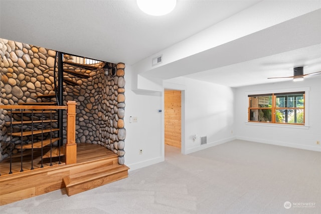 unfurnished living room featuring ceiling fan, a textured ceiling, and light colored carpet