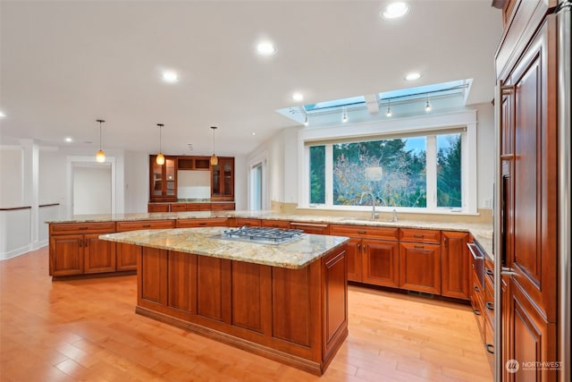 kitchen featuring sink, a kitchen island, decorative light fixtures, and stainless steel gas cooktop